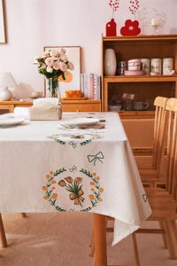 Close-up of linen tulip tablecloth with yellow floral wreath and green bow prints