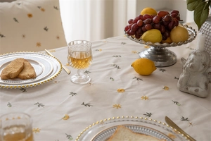 Detailed embroidery of small daisies and green leaves on a luxury cotton beige tablecloth