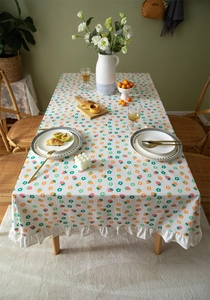 Detail of floral cotton tablecloth with orange strawberry prints and ruffled white edges