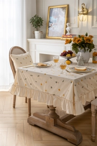 Detail of French vintage apricot floral tablecloth with elegant ruffle edge and chair covers