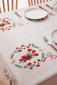 Close-up of linen tablecloth with red tulip wreath and bow prints on wooden table