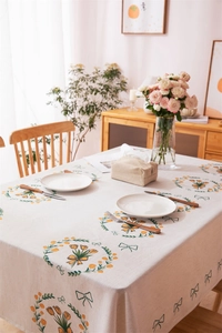 Close-up of beige linen tablecloth with yellow tulip wreaths and green bows drapes elegantly