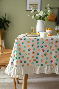 Detail of floral strawberry print cotton tablecloth featuring elegant ruffled edges