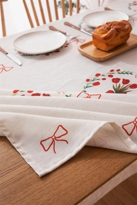 Detailed texture of cotton linen tablecloth with red tulip and bow pattern on wooden table