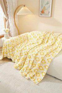 Detail of soft yellow and white geometric diamond knit sofa throw with plush texture