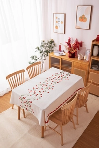 Close-up of cream rectangular tablecloth with red berries pattern and scalloped edges