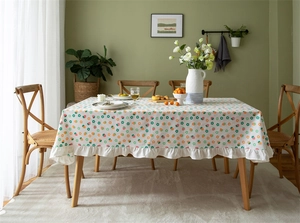 Close-up of white cotton tablecloth featuring strawberry prints and ruffled edge