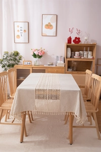 Detail of beige cotton linen tablecloth with white lace inlay and fringe tassel edge