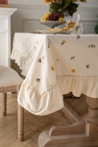 Close-up of daisy embroidery and elegant ruffle edge on apricot cotton tablecloth