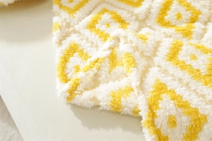 Close-up of yellow and white tufted geometric pattern on a plush sofa blanket