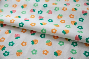 Close-up of cotton tablecloth fabric with cute strawberry and green leaf floral prints