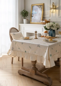 Detailed embroidery of lavender on beige cotton tablecloth with ruffled edges