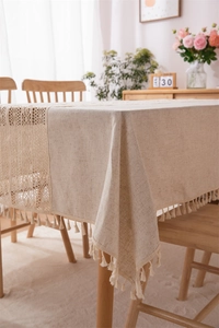 Detailed close-up of linen blend tablecloth featuring elegant lace stitching and cream tassels