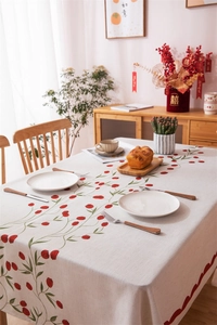Detail of red tulip floral patterns and wave edges on a beige linen texture tablecloth