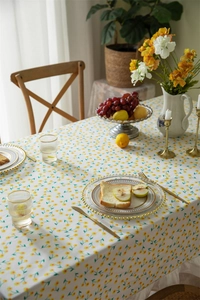 Detail of floral cotton tablecloth with yellow daisies and white ruffled edges in dining room