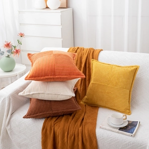 Close-up of corduroy striped patchwork pillow covers in orange, beige, and brown tones