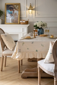 Close-up of floral embroidery and ruffle edges on a beige cotton tablecloth