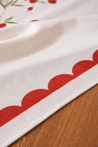Macro view of linen table runner with red scalloped edges and strawberry prints