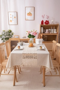 Detailed close-up of beige cotton linen tablecloth with crochet lace and woven fringe edges