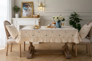 Detailed view of apricot cotton tablecloth with lavender floral embroidery and ruffled edge