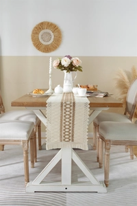 Detail of woven table runner with diamond patterns and handmade tassels on wooden table