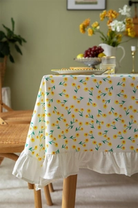 Detail of floral cotton tablecloth featuring yellow flower prints and ruffled edge design