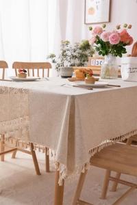 Close-up of beige linen tablecloth featuring crochet lace edges and decorative tassels