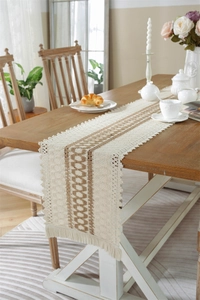 Detail of woven table runner with tassels and geometric patterns on a wooden table