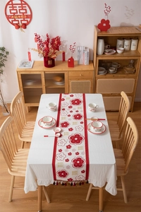 Detail van rode en beige bruiloft tafelloper met bloemmotieven en kwastjes