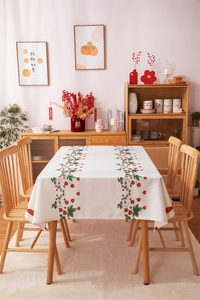 Detail of red strawberry print on cream linen tablecloth with decorative scalloped edges