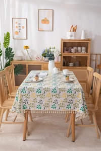 Detail of leaf pattern tablecloth showing beige tassels and thick textured cotton fabric