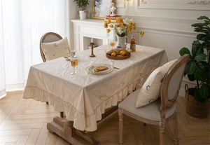 Detail of apricot cotton tablecloth with floral embroidery and elegant ruffled edges