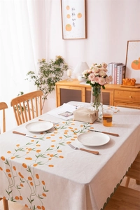 Close-up of orange tulip floral print on linen tablecloth with green wavy scalloped edges