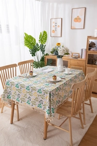 Detailed close-up of leafy print tablecloth with cream cotton tassels and woven texture
