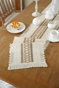 Detail of woven boho table runner with brown diamond patterns and delicate tassels