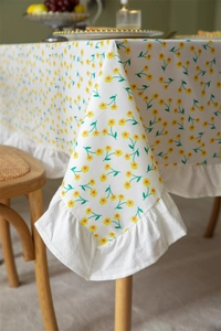 Detail of floral cotton tablecloth corner with elegant ruffled edges in a cozy home setting