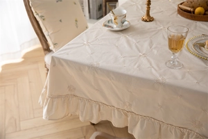 Detail of apricot floral embroidery and ruffled edge on a premium cotton round tablecloth