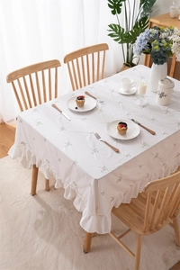 Detailed embroidery on white floral tablecloth with elegant ruffle edge decoration