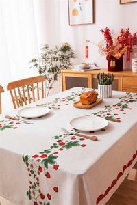 Detail of red wavy edge and strawberry print on beige rectangular tablecloth fabric