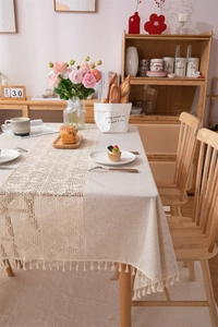 Detailed macro view of beige linen tablecloth with hollow lace patchwork and fringe tassels