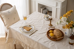 Detail of apricot cotton tablecloth with floral embroidery and ruffled edge design