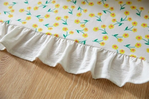 Detailed view of floral cotton tablecloth with ruffle edge and green leaf patterns