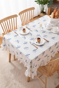 Detail of blue floral cotton tablecloth featuring ruffle edges on a wooden table