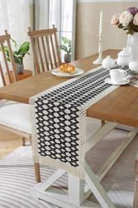Detailed texture of black and white geometric woven table runner with cream cotton tassels