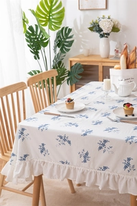 Detail of blue floral embroidery on white cotton tablecloth with ruffled hem edge