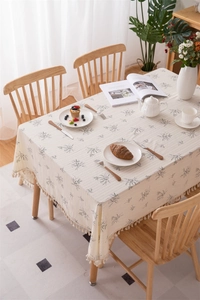 Detail of cream cotton tablecloth with botanical prints and delicate fringe edge