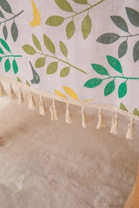 Close-up of cotton linen tablecloth showing leaf bird print and decorative fringe tassels
