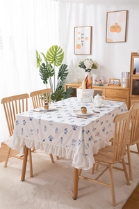 Detailed view of white floral cotton tablecloth with blue ruffles and elegant embroidery