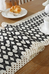 Close-up of crochet table runner with geometric star patterns and tassel lace edges