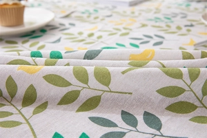 Macro shot of cotton linen tablecloth with green leaves and yellow bird patterns